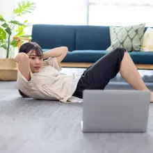 パソコンを見ながらトレーニングをしている女性